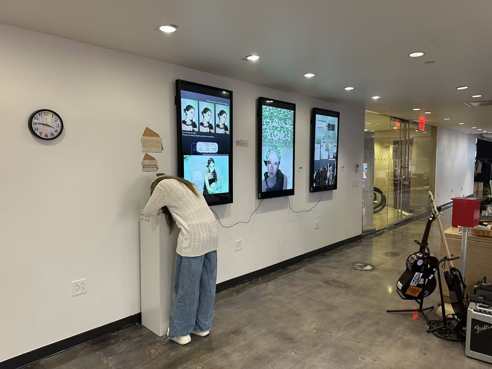 Gallery installation — person leaning in to read the screens